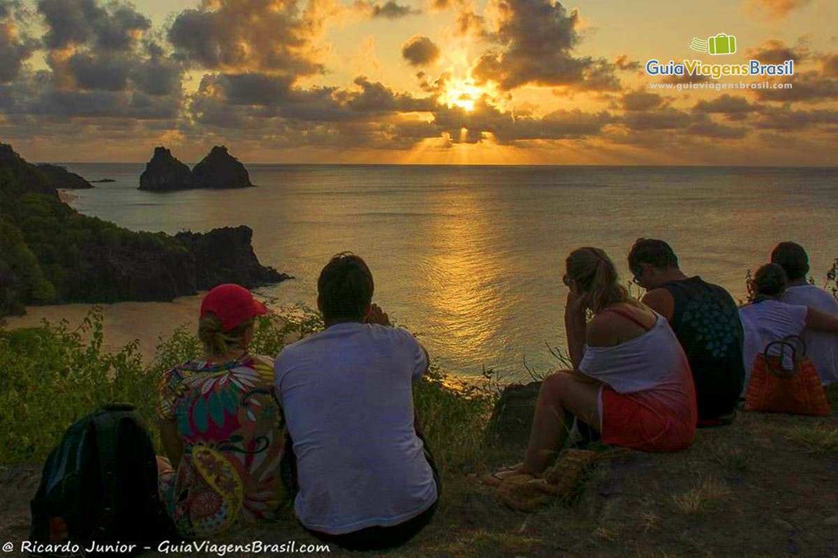 Imagem de turistas, aproveitando o entardecer na Praia do Boldro e assistindo o pôr do sol, em Fernando de Noronha, Pernambuco, Brasil.